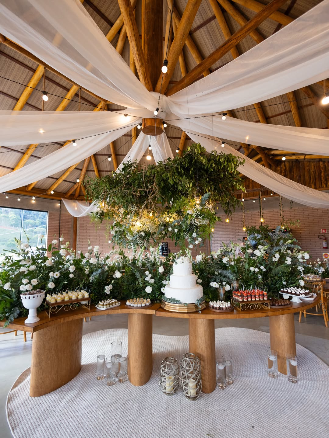 Espaço de festa com teto de tecido e centro floral suspenso